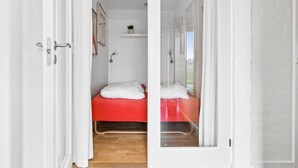 A narrow doorway leading into a room with a bed, a small shelf with a plant, and a window. - "Answald" - 6km from the sea by Interhome (Aakirkeby)