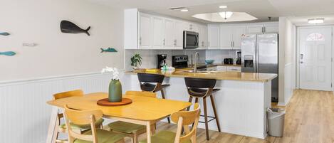 Una cocina moderna con armarios blancos, una isla central, un microondas y un refrigerador.