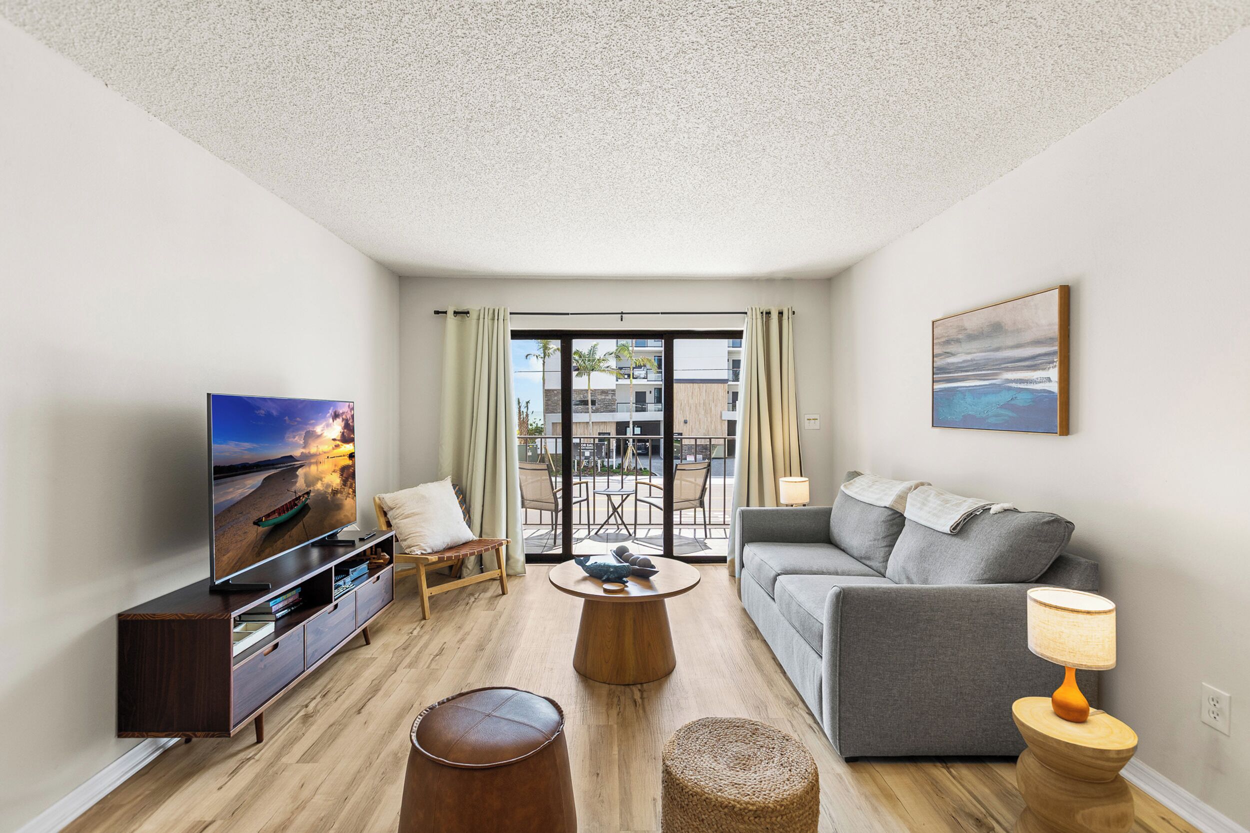 A modern living room with a flat-screen TV, a sofa, a coffee table, and a lamp.