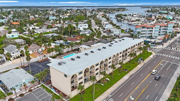 Un hotel de varios pisos con techo plano, situado cerca de la costa con un puerto deportivo.