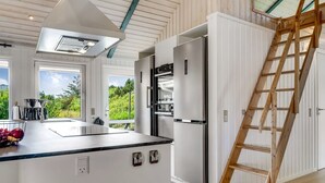 A modern kitchen with a central island, stainless steel appliances, and a wooden ladder.