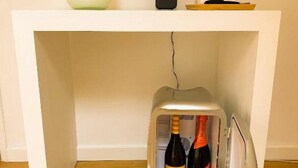 A white cabinet with a wine bottle and a wine glass inside.