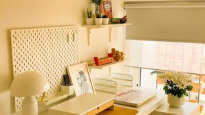 A neatly organized workspace with a pegboard, shelves, and a desk with a lamp and a notebook.