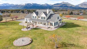A large house with a spacious front yard, a covered patio, and a view of mountains in the background.