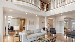 A spacious living area with a high ceiling, a curved staircase, and a view of the outdoors.