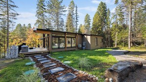 Une maison moderne dotée d’une terrasse, entourée d’une forêt.