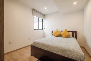 A bedroom with a bed, a window, and a wooden floor.