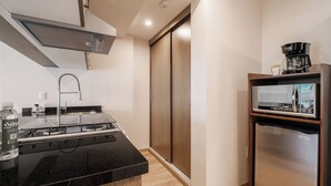 A compact kitchen with a black countertop, stainless steel appliances, and a wooden sliding door closet. - Stylish 2BR on Reforma · Near Revolución (Mexico City)