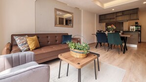 A modern living room with a brown sofa, a small table with a basket, and a dining area with chairs and a kitchen in the background. - Stylish 2BR on Reforma · Near Revolución (Mexico City)