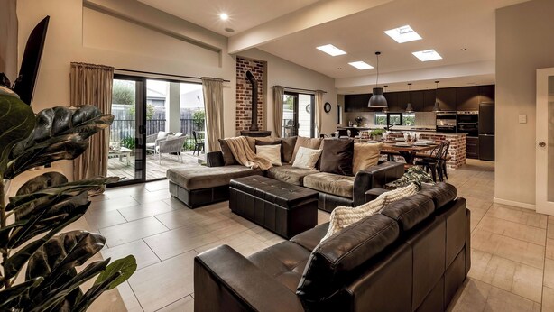 A spacious living room with a large sectional sofa, a coffee table, and a dining area with a kitchen in the background. - STYLISH AND SOPHISTICATED TWO STOREY RETREAT WITH SPARKLING POOL (Dunsborough)