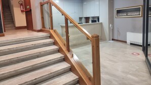 A staircase with wooden handrails leading to a reception area with a counter and cabinets. - Hotel Aba (Moncalieri)
