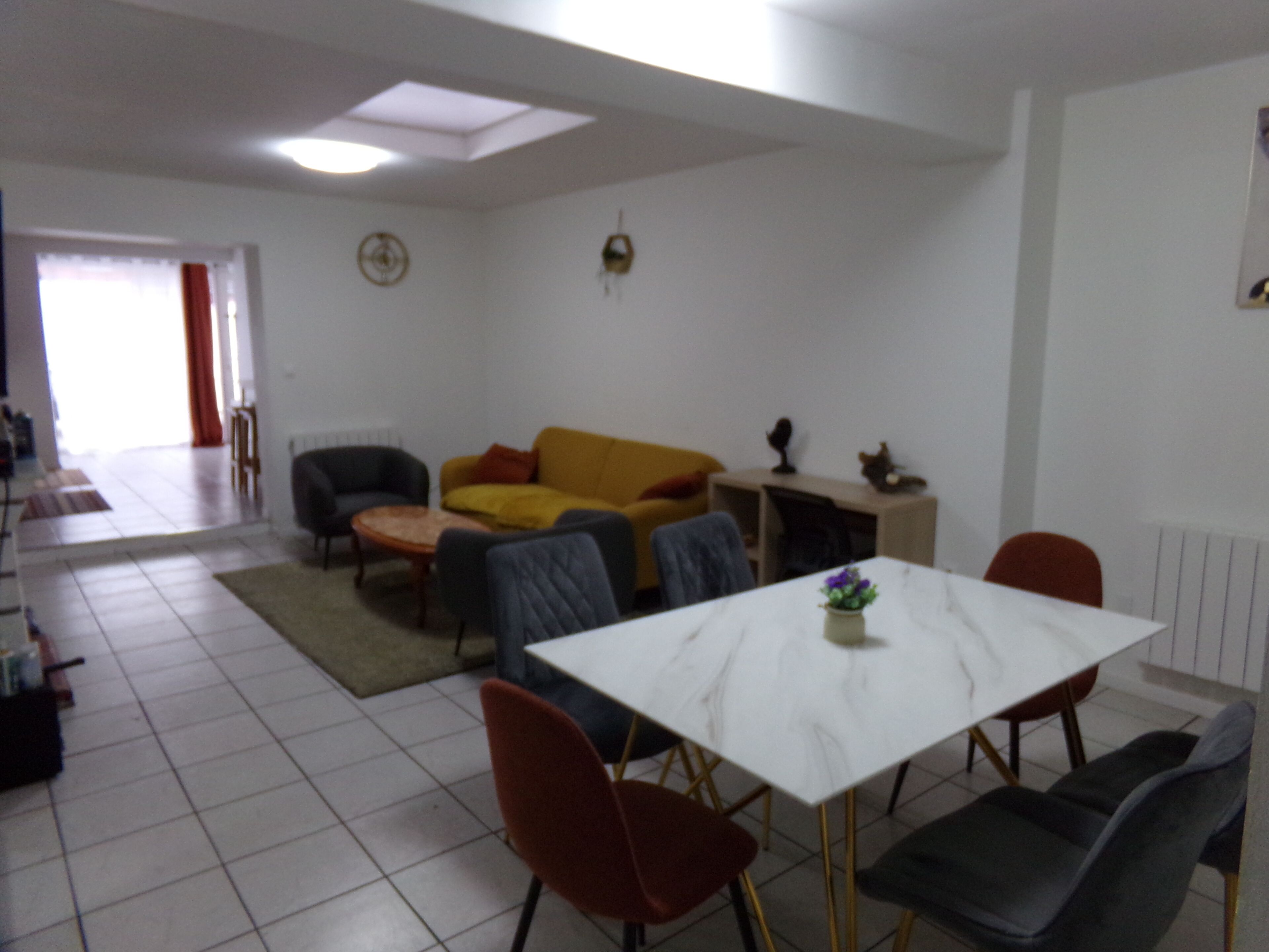 Ein Wohnzimmer mit Sofa, Sesseln, einem Esstisch und einem Kamin.