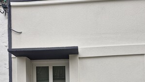A white door with a glass panel, a mailbox, and a small window with a closed shutter.