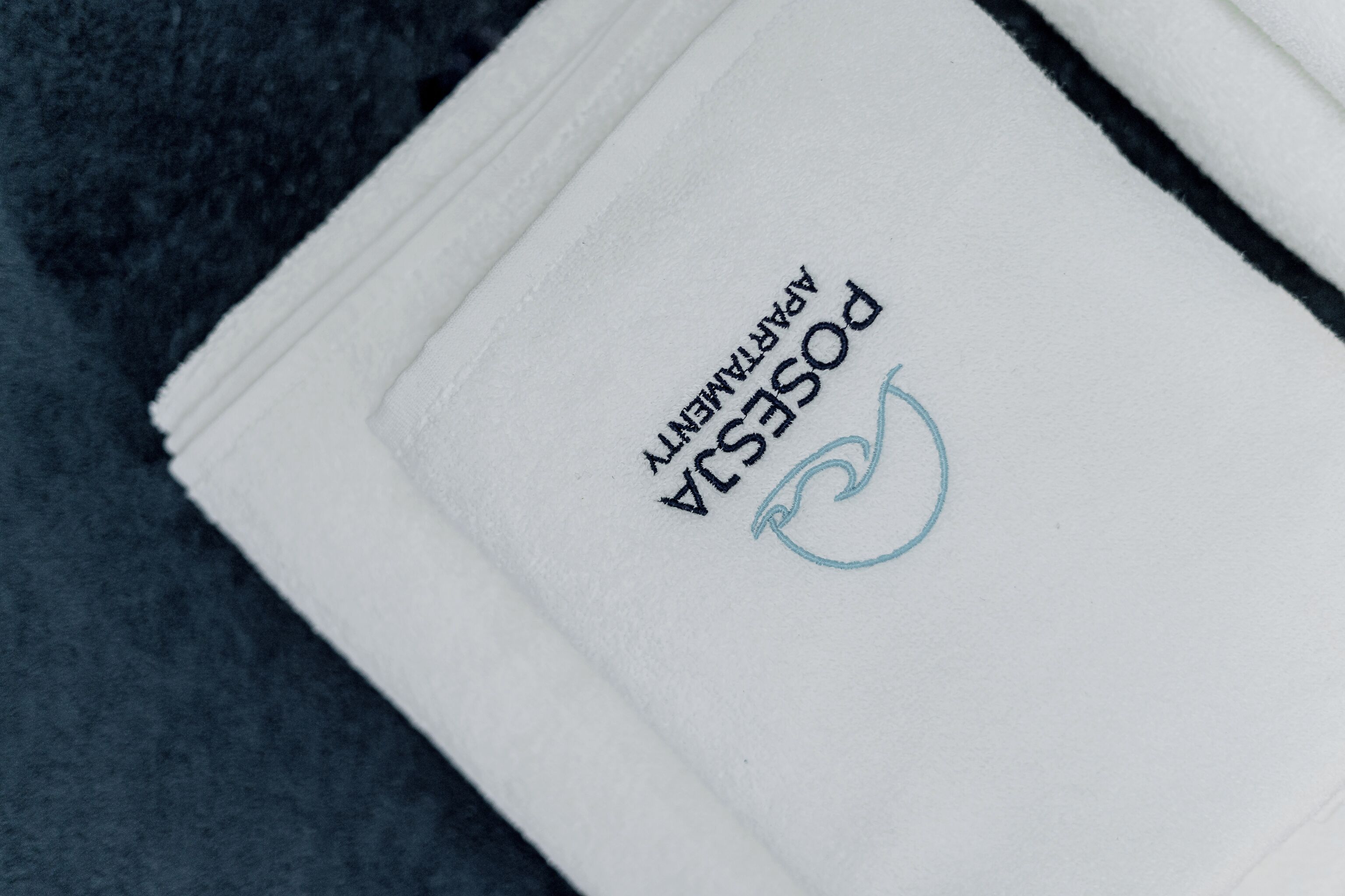 A folded white towel with the text "POSTASA" and a logo.