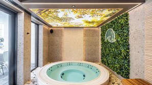 A spa area with a hot tub, a wooden bench, and a wall with greenery. - Apartments & SPA Posesja Plażowa Grzybowo by POSESJA APARTAMENTY 4a I (Grzybowo)