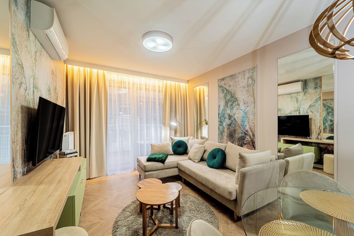 A modern living room with a sectional sofa, a glass coffee table, and a flat-screen TV.