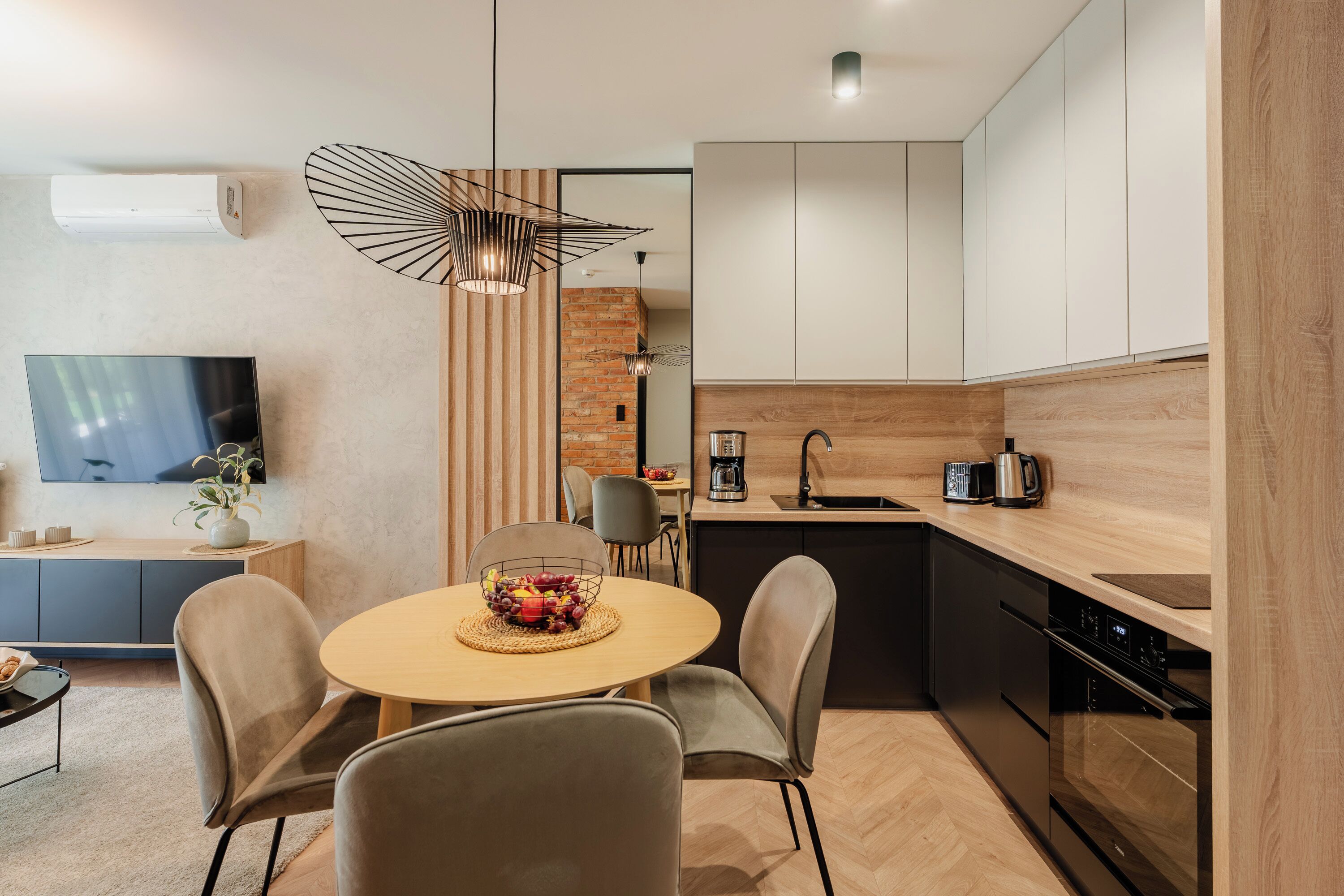Une cuisine moderne avec un coin repas, un téléviseur et un mur en briques.