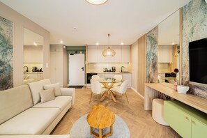 A modern living room with a sofa, a round coffee table, and a dining area with a glass table and chairs. - Apartments & SPA Posesja Plażowa Grzybowo by POSESJA APARTAMENTY 4a I (Grzybowo)