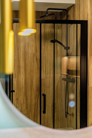 Une douche moderne avec un revêtement mural en bois et un espace clos en verre.