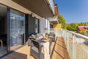 Un balcon aménagé avec du mobilier d’extérieur, une porte-fenêtre coulissante et une vue sur les environs.