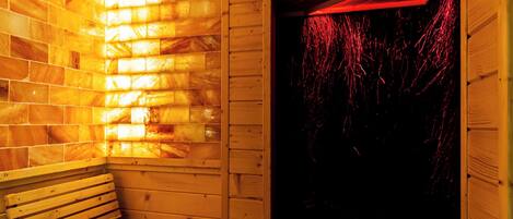 A sauna with wooden walls, a bench, and a window with red lighting.