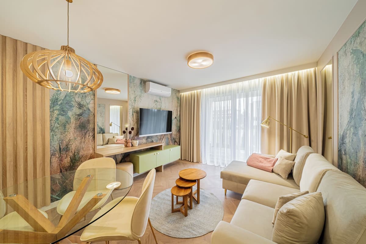 A modern living room with a sofa, a TV, a dining area with chairs, and a large window with curtains.