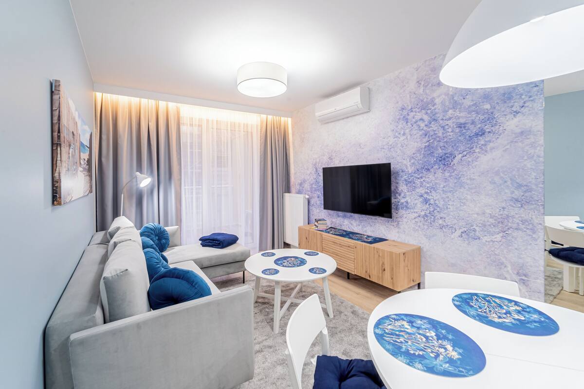 A modern living room with a sofa, a dining table, and a TV.