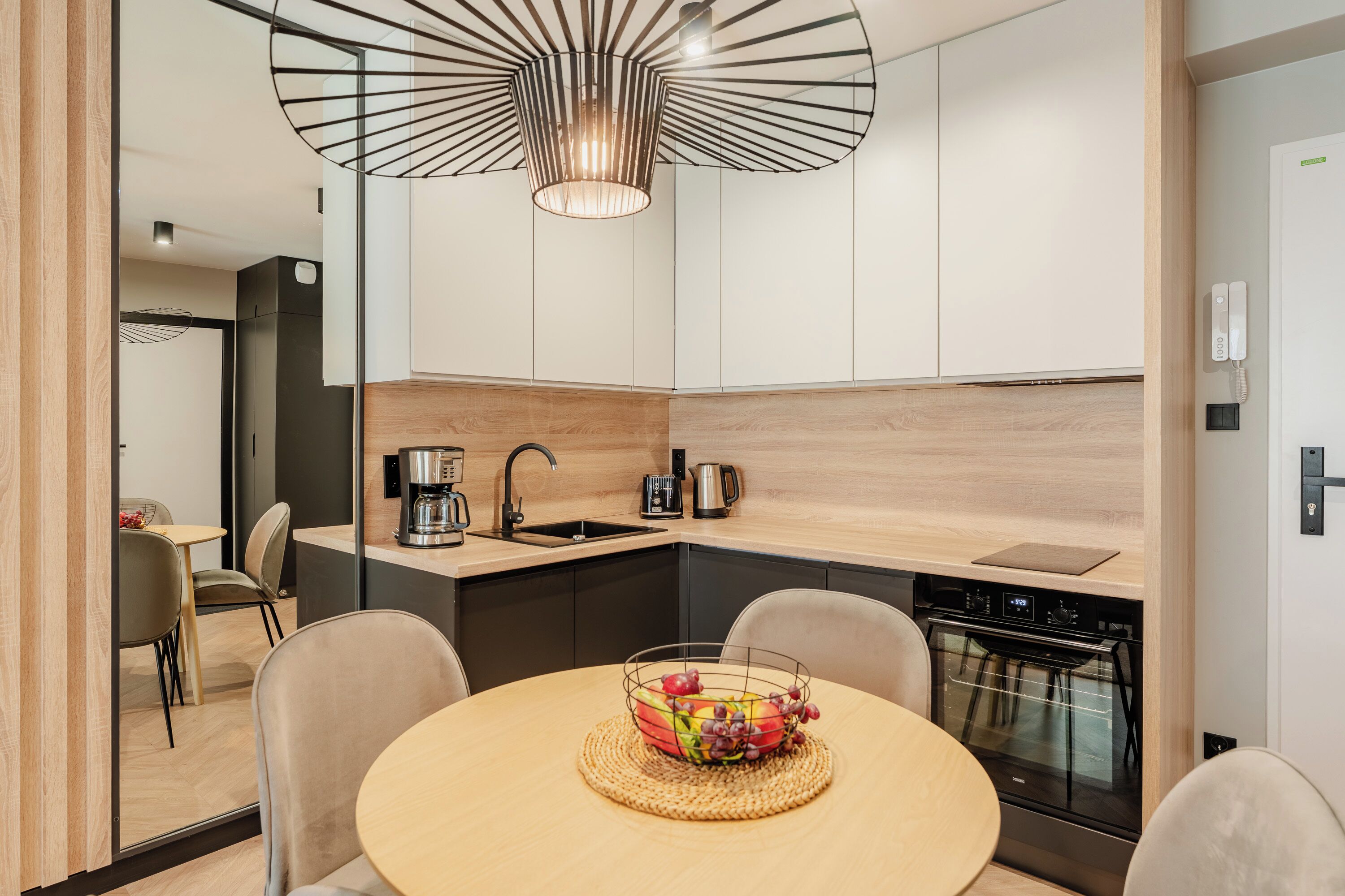 A modern kitchen with a round dining table, a fruit bowl, and a built-in oven.