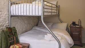 A bunk bed room with a wooden chair, a small table, and a nightstand.