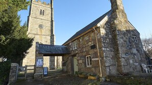 A historic stone building with a clock tower, a store sign, and a bench.