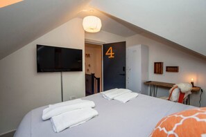 Cozy retreat with a flat-screen TV, comfortable bed, and a convenient table with a lamp.