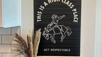 Een lijst met een poster waarop een cowboy te paard rijdt, tekst en een vaas met gedroogde planten.