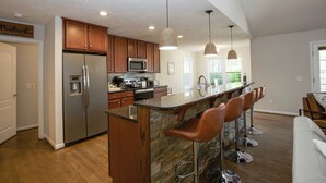 Una cocina moderna con una isla central, electrodomésticos de acero inoxidable y un protector contra salpicaduras de piedra.