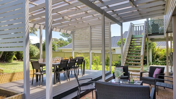 A covered outdoor patio with a table set for dining, surrounded by chairs and a sofa. - Lionel Gem – walk to Shoal Bay beaches and shops (Shoal Bay)