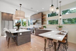 Una cocina moderna con una isla central, electrodomésticos de acero inoxidable e iluminación colgante.