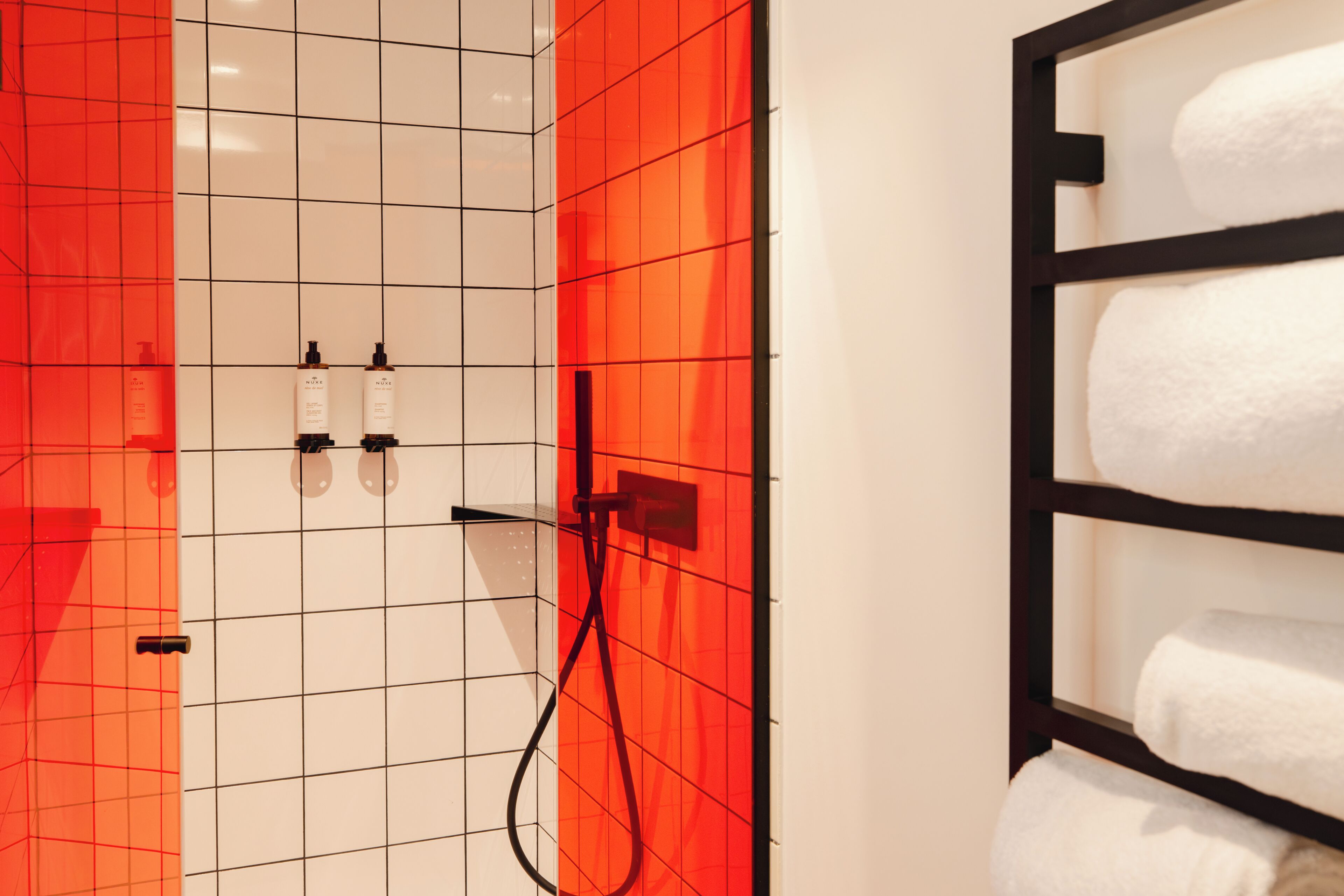 Un baño con pared de azulejos, un perchero y dos botellas en la pared.