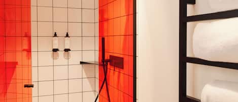 A bathroom with a tiled wall, a towel rack, and two bottles on the wall.