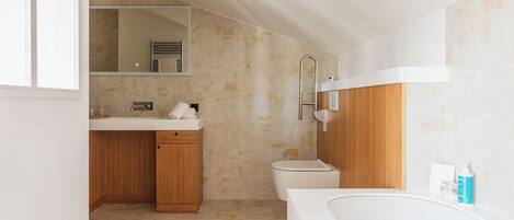 A modern bathroom with a bathtub, toilet, and vanity.