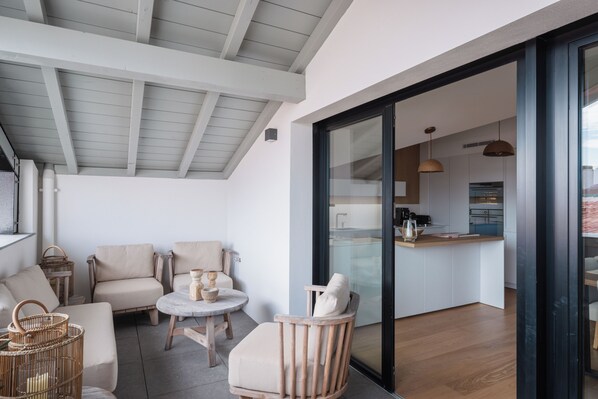 Un interior moderno con zona de comedor, sofás, cocina y puerta de vidrio que da a la cocina.