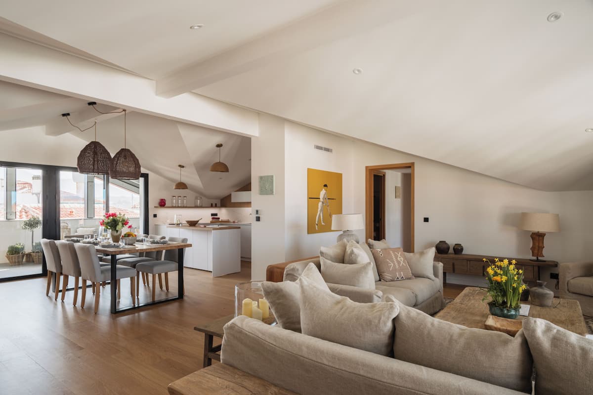 Amplia sala de estar con una mesa de comedor, sofás y una cocina al fondo.