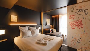 Een moderne hotelkamer met een groot bed, een zithoek en uitzicht over de stad.