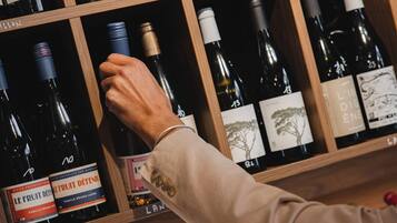 A wine rack with various bottles, a hand reaching for a bottle, and labels with text and numbers.