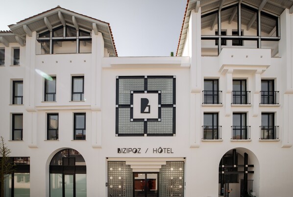 Un hotel moderno con un llamativo logo 'B', grandes ventanales y una fachada simétrica.
