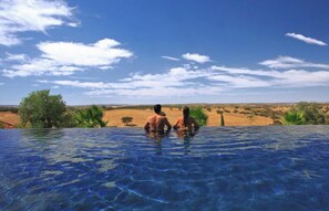 Relax by the serene pool surrounded by lush vegetation and distant hills.