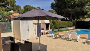 Une terrasse extérieure avec une piscine, des chaises longues et un espace salon abrité.