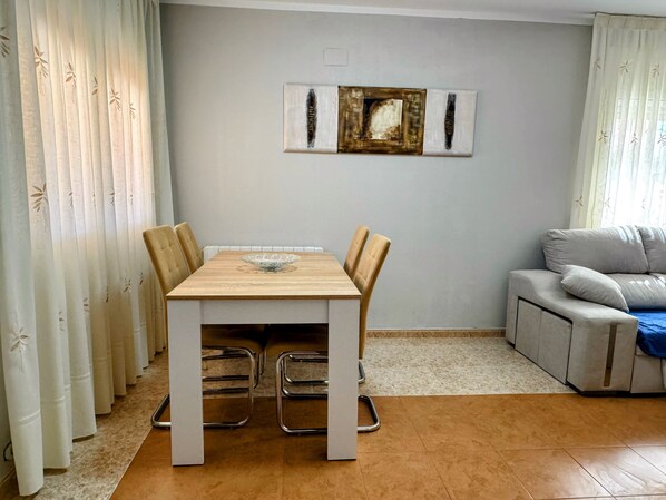 Un comedor con una mesa de madera, cuatro sillas, un cuenco de vidrio y un sofá.