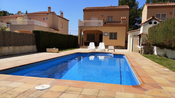 Une piscine rectangulaire dont le bord est recouvert de carreaux, entourée d’une terrasse dallée.