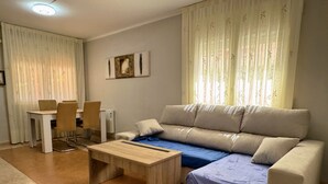 Un salon comprenant un canapé, une table basse, une table à manger avec des chaises et un radiateur.