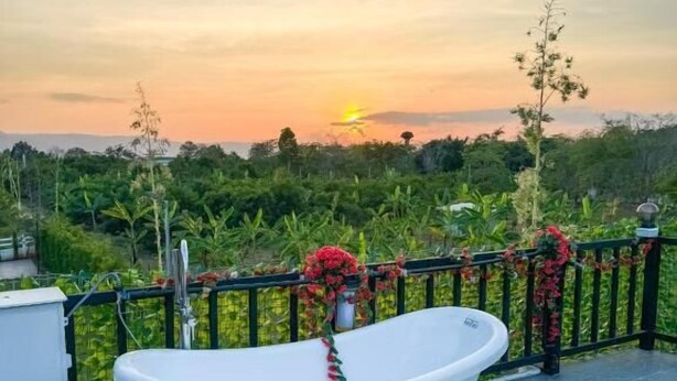 Una bañera en un balcón con vistas a una puesta de sol y follaje.