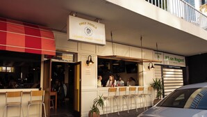 A restaurant with outdoor seating, a sign reading "ONLY FOOLS LIQUOR - FOOD - COFFEE", and a car parked in front. - Fools Inn (Cape Town)